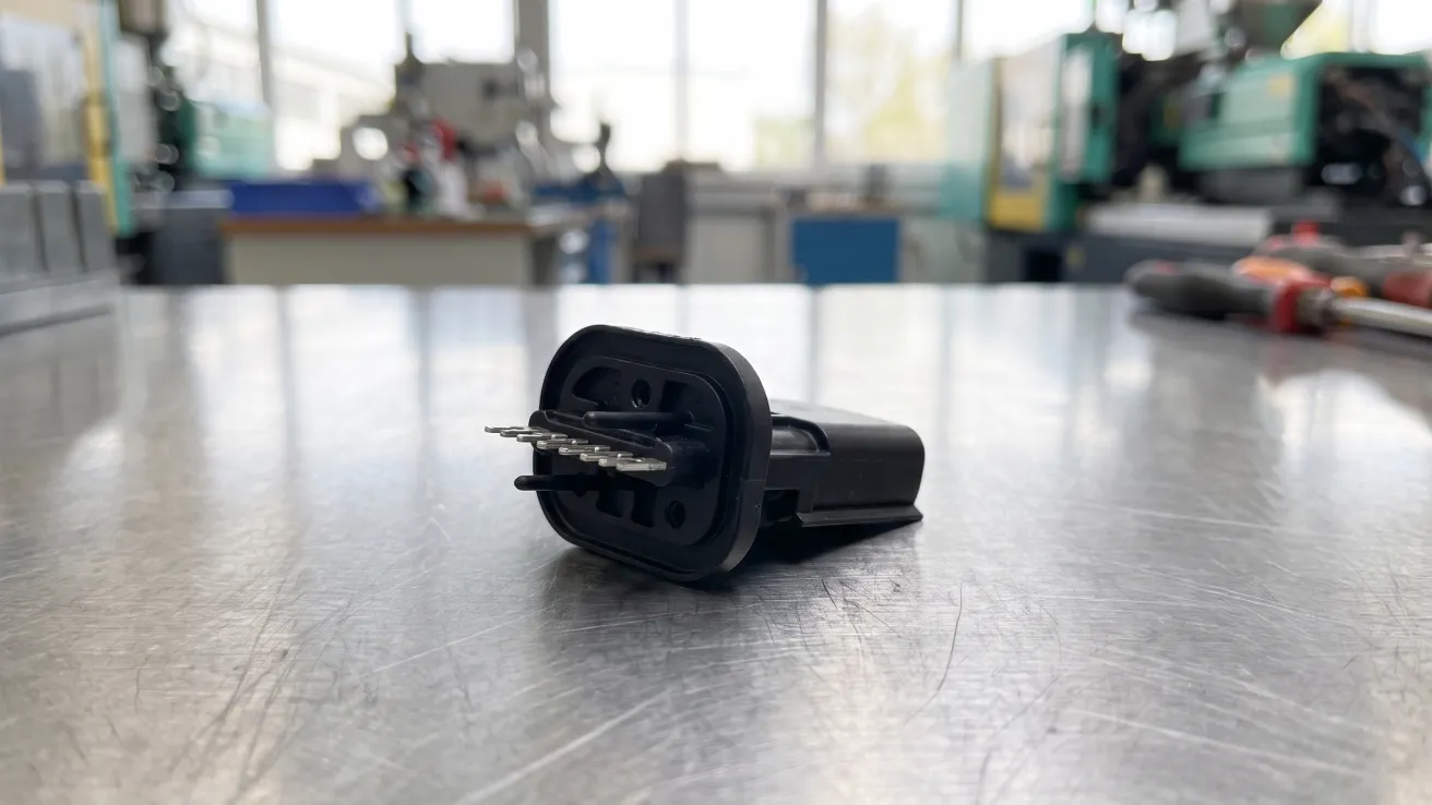 Umspritztes Kontakt- und Leadframe-Bauteil mit Stecker auf einer Edelstahl-Werkbank